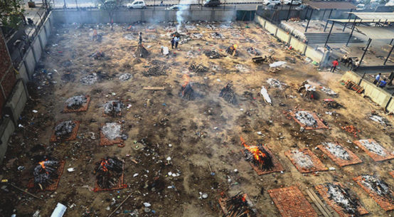 People prepare a funeral pyre for a family member who died of COVID-19 at a ground that has been converted into a crematorium for mass cremation of COVID-19 victims
